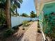 Landscaped side yard and brick walkway with lush foliage and a white vinyl privacy fence at 5802 De Palmas Ave, Holmes Beach, FL 34217