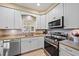 Well-lit kitchen showcasing white cabinets, stainless steel appliances, and a modern faucet, perfect for cooking and cleaning at 5869 Tidewood Ave # 7, Sarasota, FL 34231