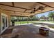 A covered patio area with a grill, fire pit, and a view of the backyard and pool at 605 15Th Avenue E Dr, Palmetto, FL 34221
