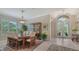 Formal dining room with plantation shutters, elegant chandelier, and a wooden china cabinet next to the front door at 7432 Ascot Ct, University Park, FL 34201