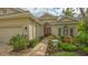 Inviting home entrance with a brick pathway, complemented by lush green shrubs and vibrant flower beds surrounding the entryway at 7432 Ascot Ct, University Park, FL 34201