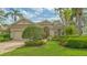 Stunning front view with lush landscaping, beautiful lawn, and a charming red door providing a welcoming entrance to the home at 7432 Ascot Ct, University Park, FL 34201