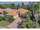 Beautiful single-story home with a red-tile roof, lush landscaping, and a brick-paved driveway at 7762 Us Open Loop, Lakewood Ranch, FL 34202