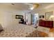 Comfortable main bedroom features wood floors, ceiling fan, dresser, and a view to the ensuite bath at 7762 Us Open Loop, Lakewood Ranch, FL 34202