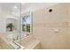 Elegant bathroom with a soaking tub, glass-enclosed shower, and neutral tile at 8122 Spring Marsh Dr, University Park, FL 34201