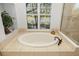 Bathroom featuring a soaking tub next to a window, with a glass enclosed shower to the right at 8122 Spring Marsh Dr, University Park, FL 34201