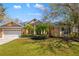 Traditional one-story home featuring a two-car garage, mature landscaping, and tan stucco exterior at 8122 Spring Marsh Dr, University Park, FL 34201