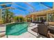 Relaxing screened-in pool area with ample seating, lush tropical landscaping, and a bright blue sky overhead at 8122 Spring Marsh Dr, University Park, FL 34201