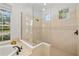 Elegant bathroom with a glass-enclosed shower, adjacent to a soaking tub under a window at 8122 Spring Marsh Dr, University Park, FL 34201