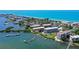 Expansive aerial shot featuring waterfront buildings, boat docks, and a sandy beach at 8735 Midnight Pass Rd # 105B, Sarasota, FL 34242