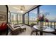 Enclosed balcony with a view of the water, comfortable seating, and a table for enjoying the scenery at 8735 Midnight Pass Rd # 105B, Sarasota, FL 34242