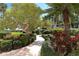 Beautiful landscaping featuring mature trees, flowering plants, and manicured shrubs adorns the walking path to the building at 8735 Midnight Pass Rd # 105B, Sarasota, FL 34242