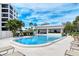 Community pool and spa with lounge chairs, pool house, and lush landscaping offers a resort-like living experience at 8735 Midnight Pass Rd # 105B, Sarasota, FL 34242