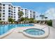 A lovely community pool with a hot tub are surrounded by lounge chairs and an apartment complex set amongst palm trees at 8735 Midnight Pass Rd # 105B, Sarasota, FL 34242