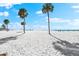 Beautiful beachfront scene with white sand, palm trees, and clear blue sky at 1035 Seaside Dr # 308, Sarasota, FL 34242