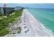 Aerial view of beachfront condo, beachgoers, umbrellas, and crystal clear turquoise water at 1055 Gulf Of Mexico Dr # 405, Longboat Key, FL 34228