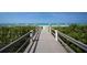 Picturesque boardwalk leading to a stunning beach with clear blue water and white sand, perfect for a relaxing getaway at 1055 Gulf Of Mexico Dr # 405, Longboat Key, FL 34228