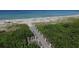 Aerial view of beach access from a wooden walkway through lush greenery at 1055 Gulf Of Mexico Dr # 405, Longboat Key, FL 34228