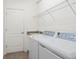 Well-lit laundry room features modern washer and dryer, storage shelf, and granite countertop sink at 11412 Autumn Leaf Way, Bradenton, FL 34212