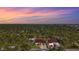 Scenic aerial view of homes surrounded by lush greenery and a colorful sky at 115 Solana St, North Port, FL 34287