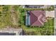 Aerial view of a home with a screened in pool surrounded by vibrant green landscaping and wooded areas at 115 Solana St, North Port, FL 34287