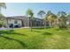 Expansive backyard with manicured lawn and view of screened-in lanai and pool at 115 Solana St, North Port, FL 34287
