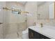 Modern bathroom with a glass-enclosed shower featuring gold hardware, a stylish vanity, and unique textured tiles at 115 Solana St, North Port, FL 34287