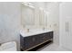 Bathroom featuring dual sinks with white marble countertops, dark cabinetry, and sleek white tiled walls at 115 Solana St, North Port, FL 34287