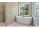 Stylish bathroom showcasing a large soaking tub, glass-enclosed shower, and a window offering scenic outdoor views at 115 Solana St, North Port, FL 34287