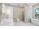 Luxurious bathroom with dual sink vanity, modern toilet, glass enclosed shower and standalone tub under a large window at 115 Solana St, North Port, FL 34287