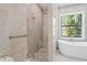 Modern bathroom with a glass shower and a soaking tub by a window boasting serene views of the lush outdoors at 115 Solana St, North Port, FL 34287