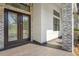 Modern front entryway featuring a tiled porch, stone accents and a large wooden double door at 115 Solana St, North Port, FL 34287
