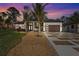 Beautiful front exterior of home with well-manicured landscaping, dark wood garage and white stone accents at 115 Solana St, North Port, FL 34287