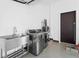 Bright laundry room featuring stainless steel washer and dryer, utility sink, and white walls at 115 Solana St, North Port, FL 34287