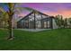 Exterior view of a screened in pool area with palm trees and a beautiful lawn at 115 Solana St, North Port, FL 34287