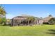 The backyard features a large screened in lanai with palm trees and lush green lawn, perfect for entertaining at 12736 Penguin Dr, Bradenton, FL 34212