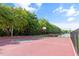 Outdoor basketball court with tall fences, mature landscaping, court lines, and a basketball hoop at 12736 Penguin Dr, Bradenton, FL 34212