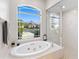 Bright bathroom with garden tub and a walk-in shower under a large arched window at 12736 Penguin Dr, Bradenton, FL 34212