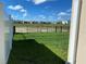 Large, grassy backyard featuring a white vinyl fence, black metal fence, and views of the surrounding community at 13393 Golden Lime Ave, Spring Hill, FL 34609