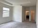 A bright, carpeted bedroom featuring a tray ceiling, a large window, and closet and bathroom access at 13393 Golden Lime Ave, Spring Hill, FL 34609
