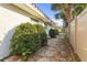 Stone walkway along the house featuring a tidy walkway alongside the house, lush plantings, and privacy fence at 1354 Lucaya Ave, Venice, FL 34285