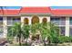 Beautiful condo complex with an eye-catching red tiled roof, palm trees, lush green grass, and inviting arched entryways at 137 Avenida Messina # 3, Sarasota, FL 34242