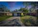 Home at dusk featuring a front lawn, attached garage, and mature landscaping at 1410 24Th E Ave, Bradenton, FL 34208