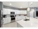 Bright, all-white kitchen with stainless steel appliances and an island with pendant lighting at 14355 59Th E Cir, Bradenton, FL 34211