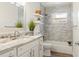 Well lit bathroom features marble counters, white cabinets, and tub with gray tile surround at 1622 Wisconsin Ln, Sarasota, FL 34239