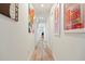 Hallway with neutral walls, wood look floors and eclectic art on the walls at 1622 Wisconsin Ln, Sarasota, FL 34239