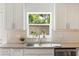 Bright kitchen showcasing white cabinets, light countertops, stainless steel sink, and a window with lush views at 1622 Wisconsin Ln, Sarasota, FL 34239