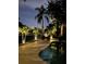 Backyard with pool, lighting, palm trees, and lounge chairs at twilight at 1633 Ridgewood Ln, Sarasota, FL 34231
