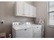 Laundry room featuring a new white washer and dryer with overhead cabinets for additional storage at 16810 Scuba Crest St, Wimauma, FL 33598