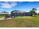 The spacious backyard includes a screened pool, green lawn, and cozy patio furniture at 1714 Coral Sands Ct, Venice, FL 34293